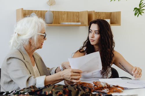 Free Elderly woman and young woman discussing fabric designs in a fashion meeting. Stock Photo